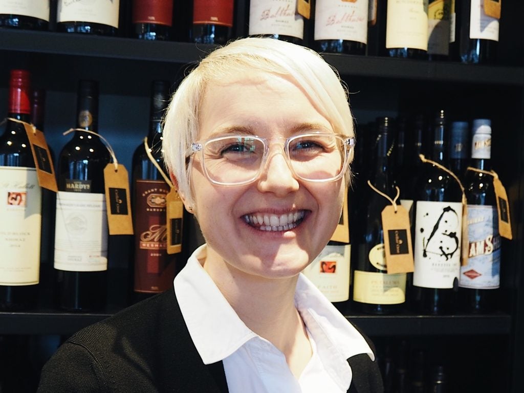 Caroline Thompson-Hill smiling in front of wine racks