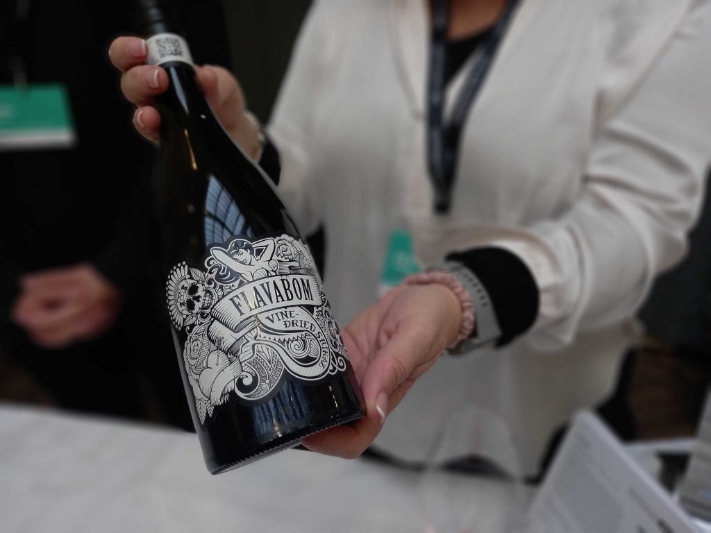 A close up of Flavabom wine bottle being held by a women in a white shirt