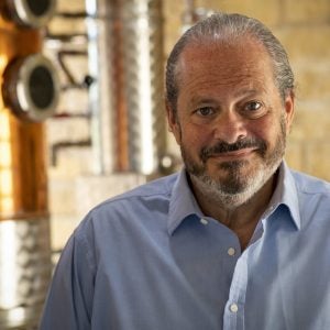 Man in light blue shirt in distillery, looking at camera.