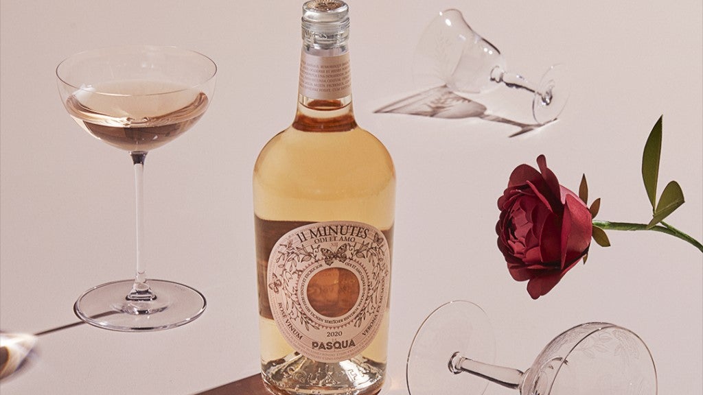 rose wine bottle on light pink background with glasses of wine and rose
