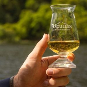 A person holding a glass of whiskey embossed with the Fercullen brand
