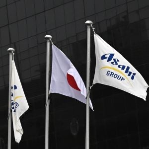 A Japanese national flag and Asahi Group Holdings flags in front of the company’s headquarters in Tokyo, Japan, on 3 October 2025. Credit: Soichiro Koriyama/Bloomberg via Getty Images