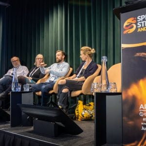 Panel of men and women on stage speaking.