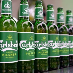 PENANG, MALAYSIA - 3 JUNE 2023: A row of Carlsberg's beer bottles display on food truck stall at a outdoor birthday party. Carlsberg is a Danish multinational brewer.