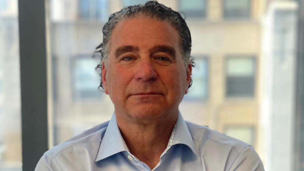 Man in light blue shirt looking at camera, dark hair. 