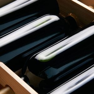 close-up shot of wine bottles in wooden crate on wood table.
