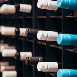 Wine bottles in vertical shot stacked on racks shot with limited depth of field. Red wine on shelf. Wine bottles lined up and stacked on shelves in a luxury private collection collectible wine store.